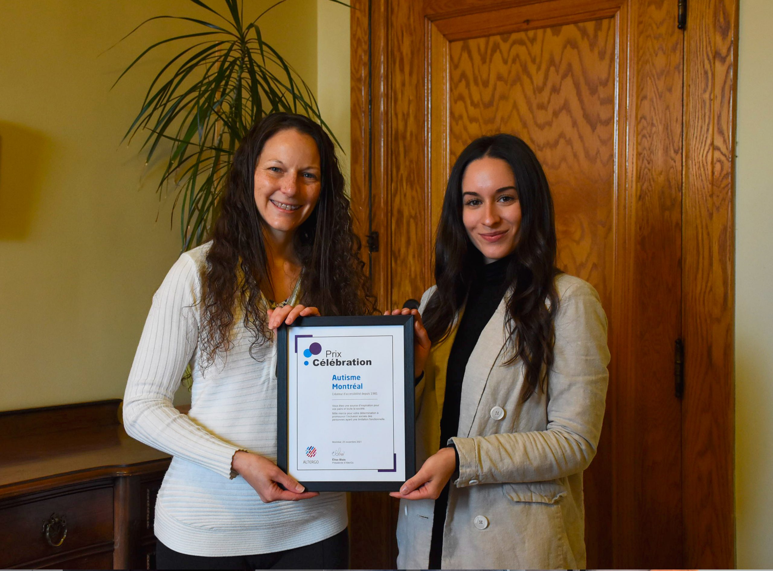 2 représentantes d'Autisme Montréal tiennent la plaque de reconnaissance en souriant.